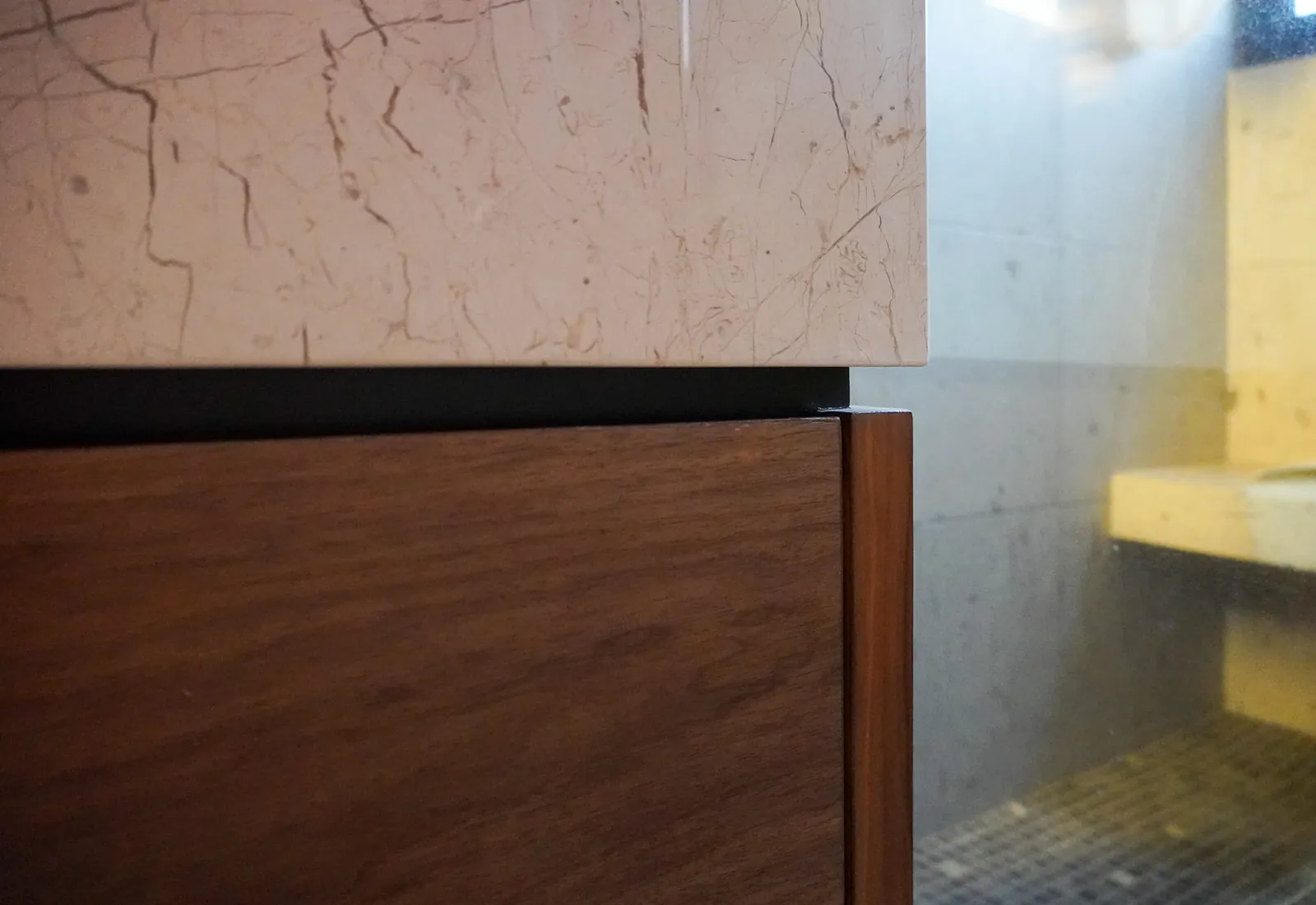 Detalle de la junta entre cubierta de mármol y frente de madera en un mueble Ágora